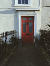 A welcoming front door painted bright red with a neat pathway leading up to it.