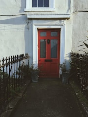 Bright red front door with decorative wreath and polished brass knocker.