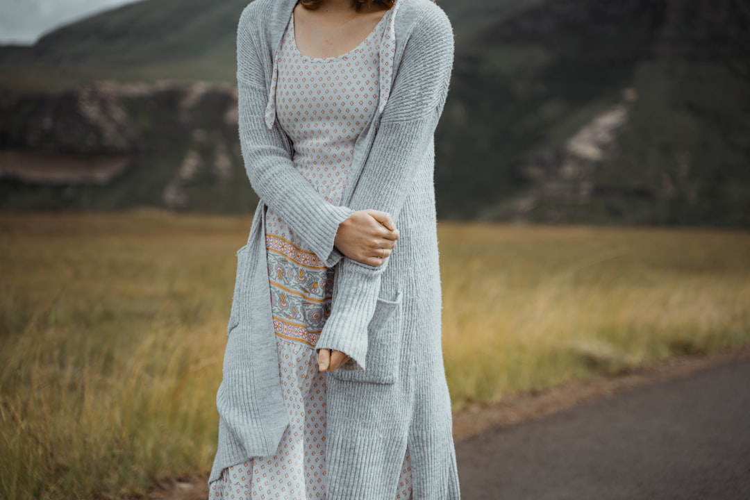 woman in gray long sleeve dress standing on road during daytime