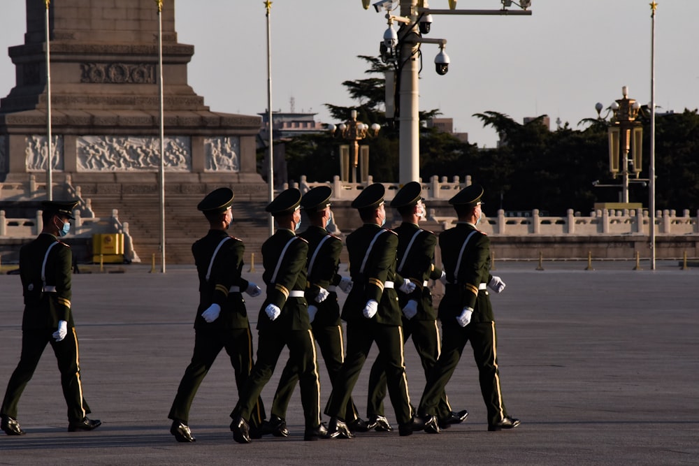 men in black and white uniform standing on gray concrete road during daytime