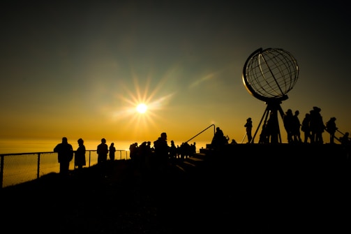 silhouette of people standing on the beach during sunset