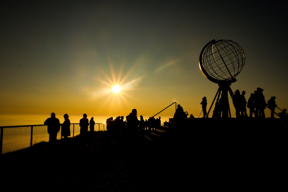 silhouette of people standing on the beach during sunset