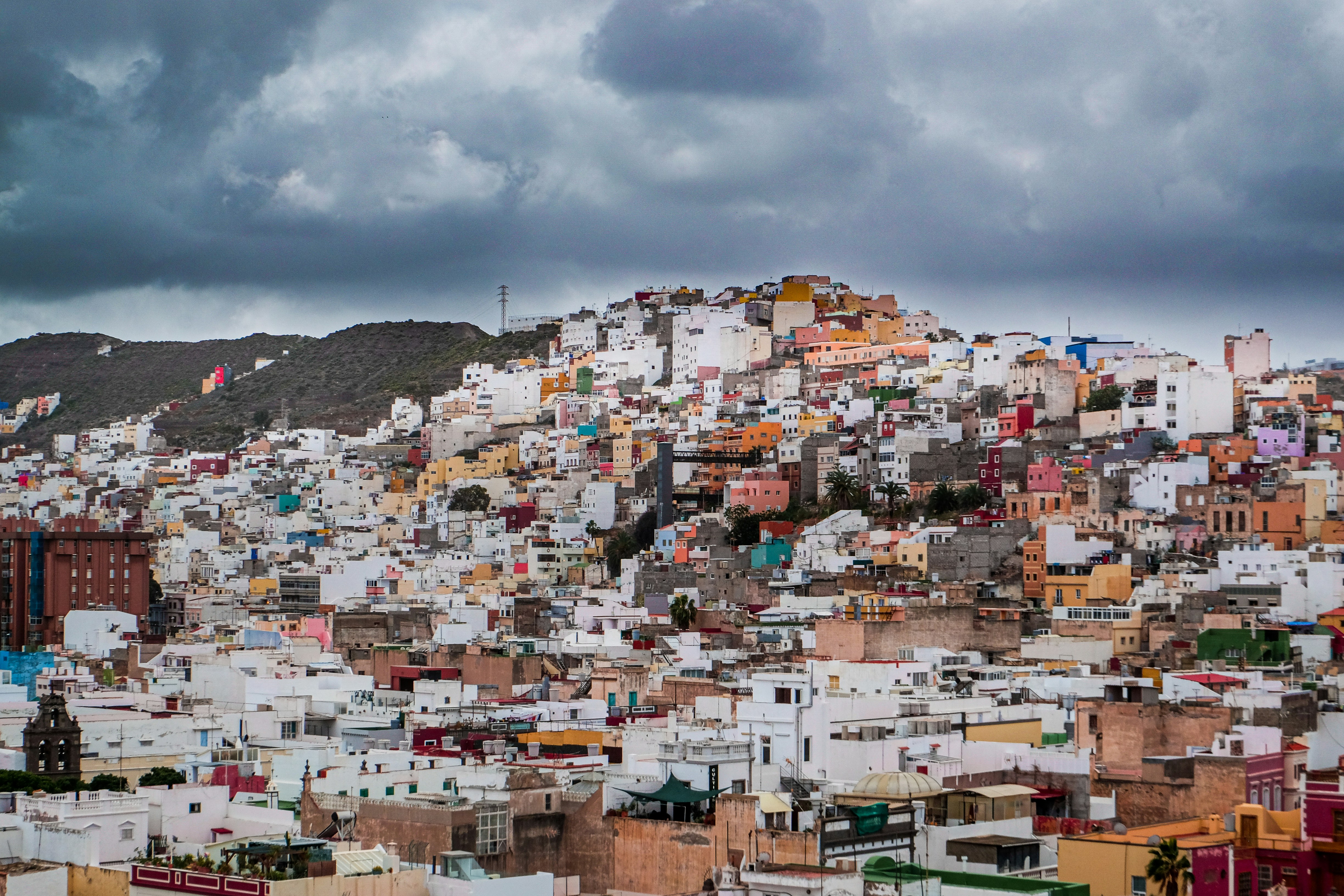 Maisons blanches et brunes sur la colline sous les nuages blancs pendant la journée