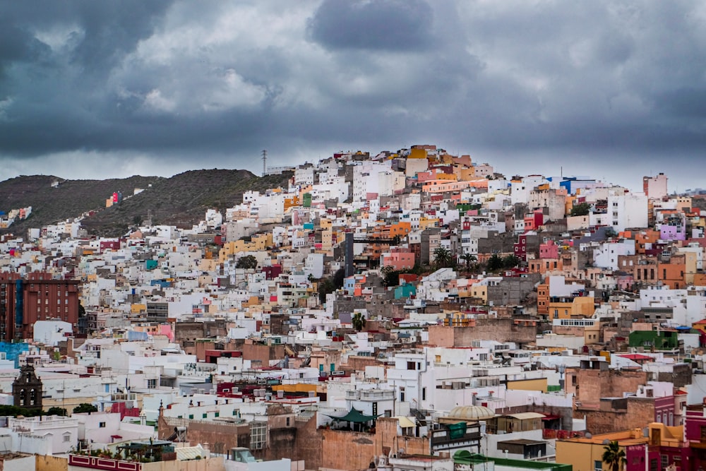white and brown houses on hill under white clouds during daytime