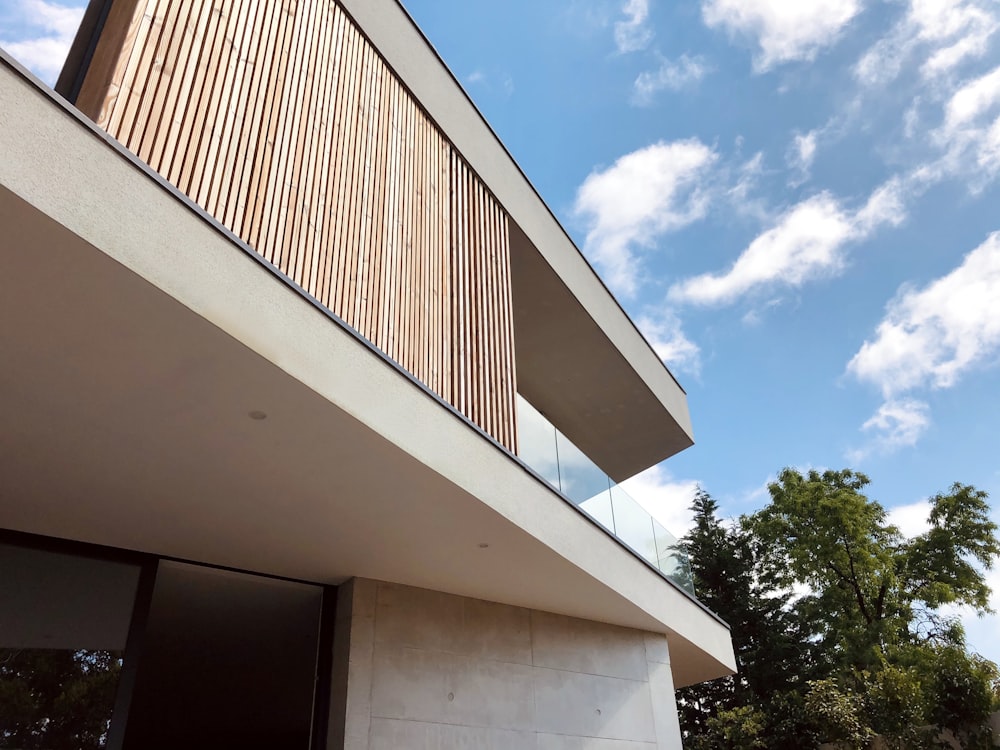 white concrete building near green trees under white clouds during daytime