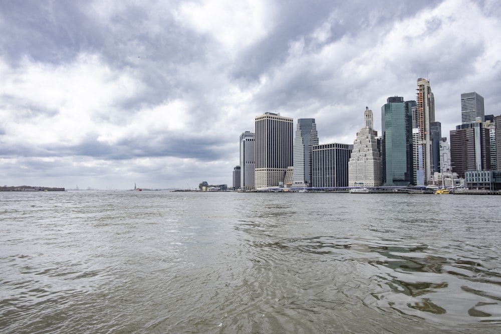 Cuerpo de agua cerca de los edificios de la ciudad bajo nubes blancas y cielo azul durante el día