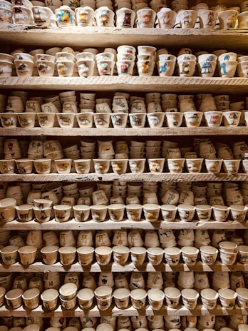 An assortment of unique cups displayed on a rustic shelf, showcasing different shapes and textures.