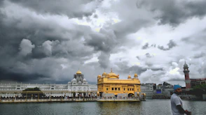 brown and white concrete building near body of water under gray clouds