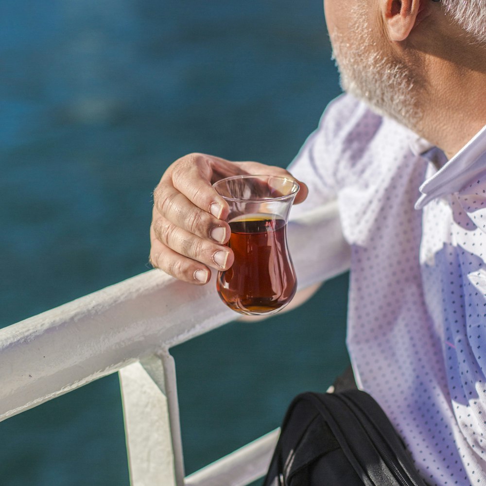 man in white and purple checkered dress shirt holding clear glass mug