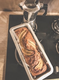 A warm loaf of banana bread cooling on a wooden rack with a rustic kitchen background.