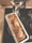 A freshly baked banana bread loaf sits in a rectangular metal pan on a stovetop, next to a silver moka pot. The loaf has slices of banana baked into its top, giving it a rustic appearance.