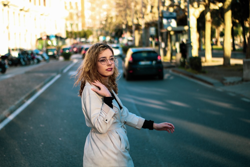 woman in white long sleeve shirt standing on road during daytime