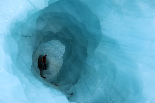 person in black jacket sitting on ice in Glaciar Exploradores Chile