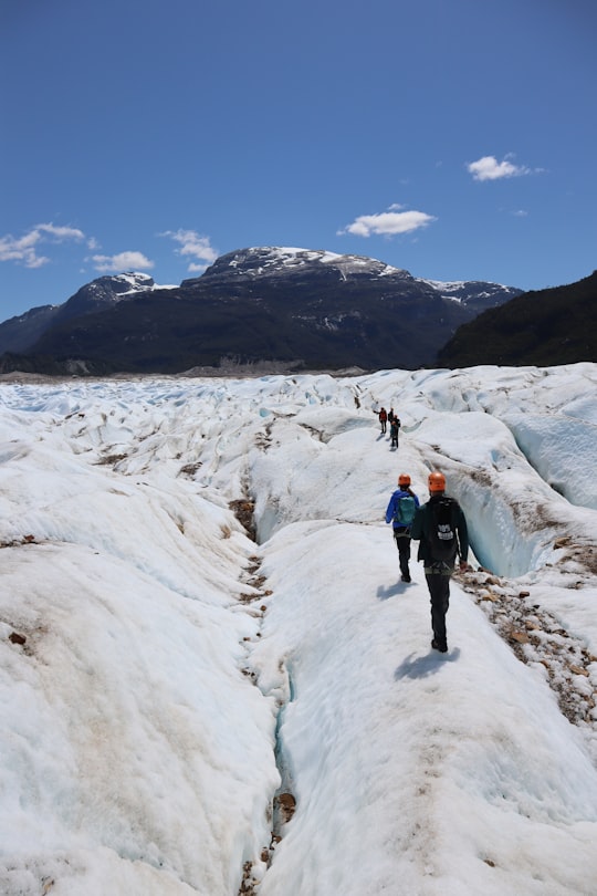 2 person walking on snow covered field during daytime in Glaciar Exploradores Chile