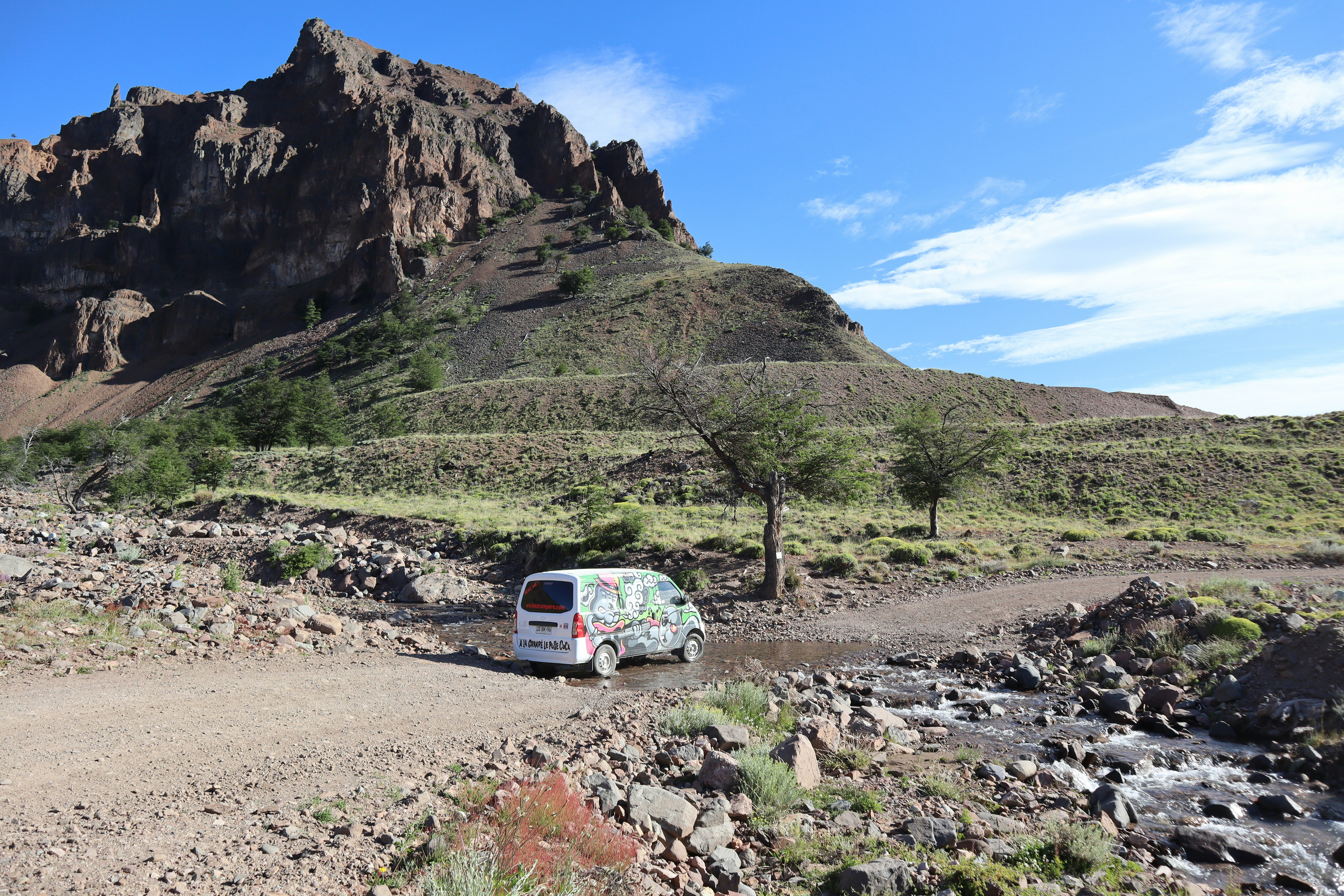 white van on dirt road near mountain during daytime