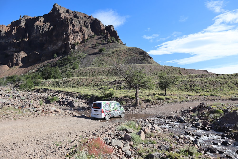 white van on dirt road near mountain during daytime