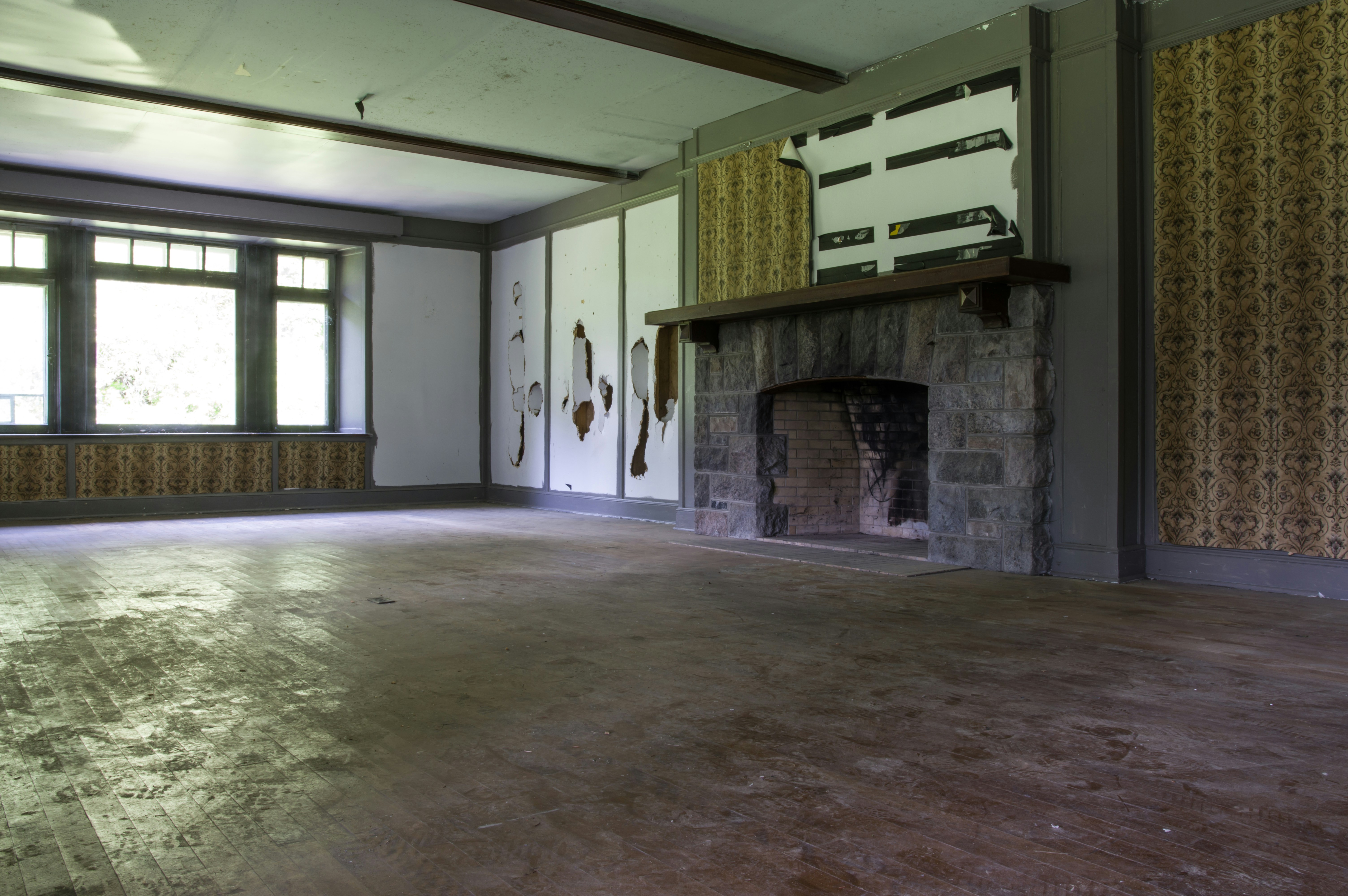 A cozy living room before renovation, with outdated wallpaper and worn-out furniture.