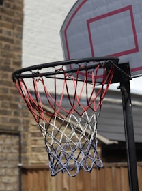 A colorful lineup of basketball nets in various shades displayed against a rustic brick wall, showcasing durability and style.