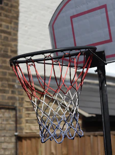 Vibrant colored basketball nets displayed against a wooden fence.