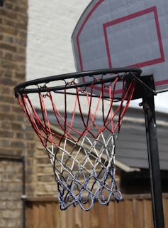 A colorful lineup of basketball nets in various shades displayed against a rustic brick wall, showcasing durability and style.