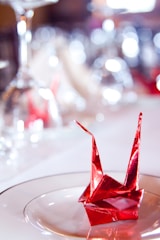 Close-up of elegant business cards with vibrant red origami crane logo on a clean white background.