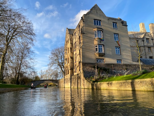 brown concrete building near river under blue sky during daytime in River Cam United Kingdom