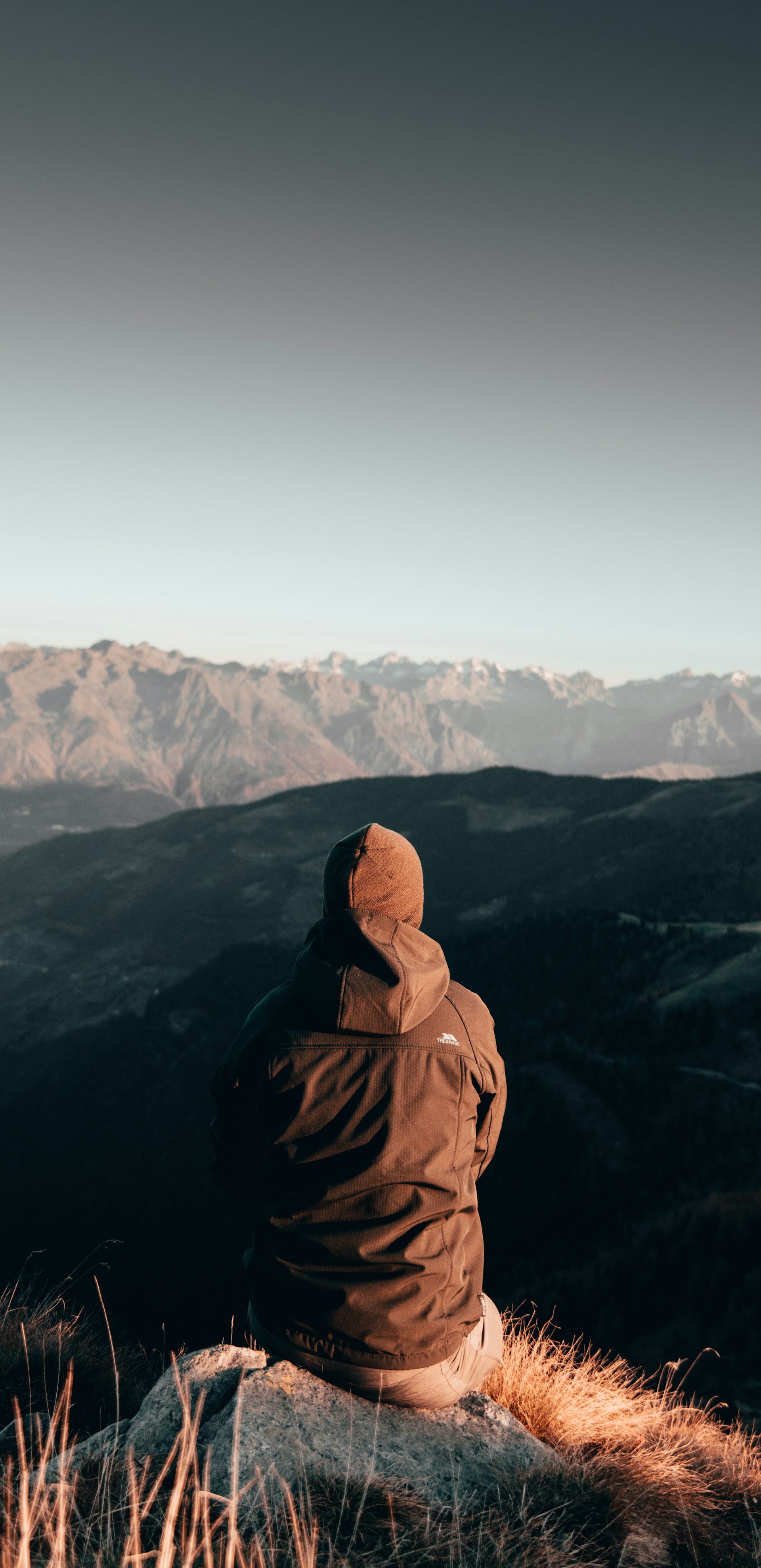 person in brown hoodie standing on top of mountain during daytime