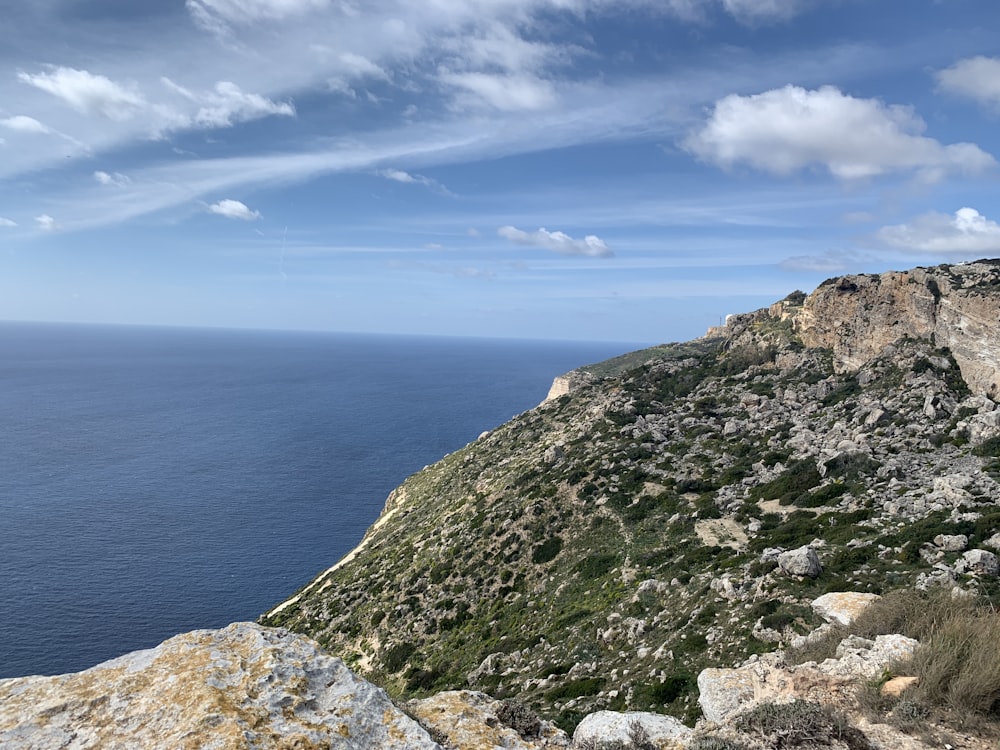 green and gray rock formation beside blue sea under blue sky during daytime