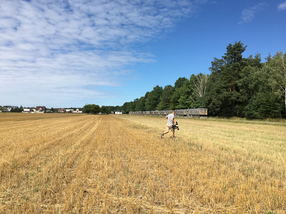 man in white shirt and black pants walking on brown grass field during daytime