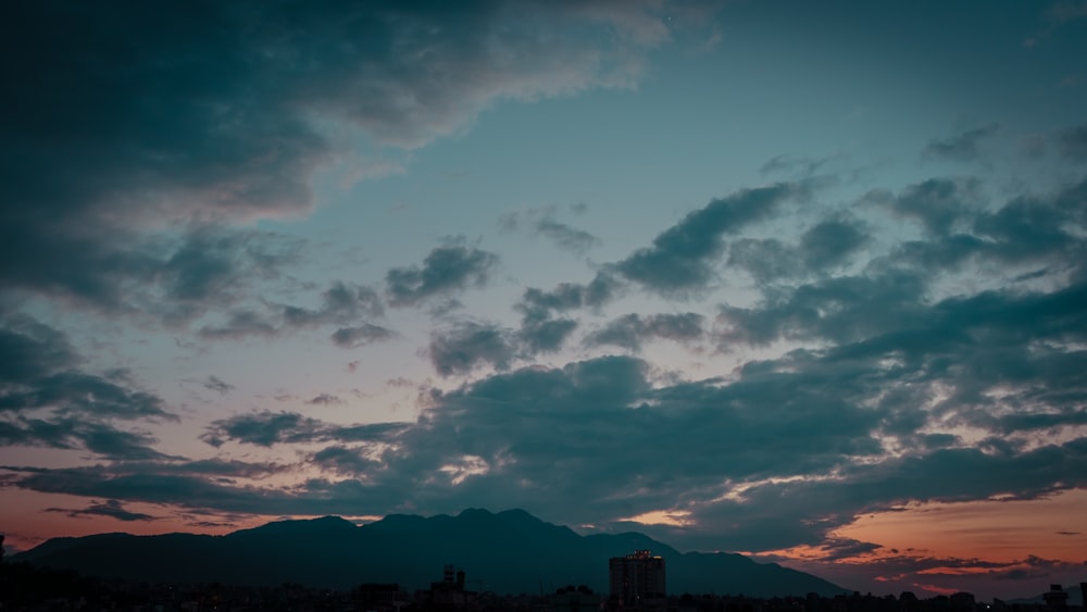 silhouette of mountain under cloudy sky during daytime