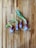 Four sprouting onions with green shoots are placed on a wooden surface. The onions have a mix of purple and white colors with roots visible at the bottom.