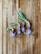 Four sprouting onions with green shoots are placed on a wooden surface. The onions have a mix of purple and white colors with roots visible at the bottom.