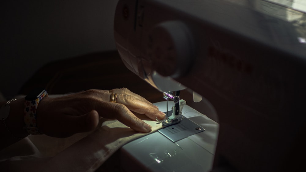 person playing sewing machine with pink sewing thread