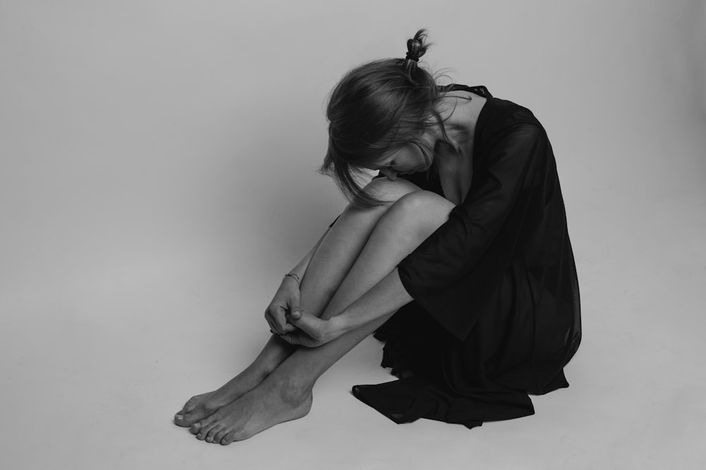 donna in vestito nero che si siede sul pavimento