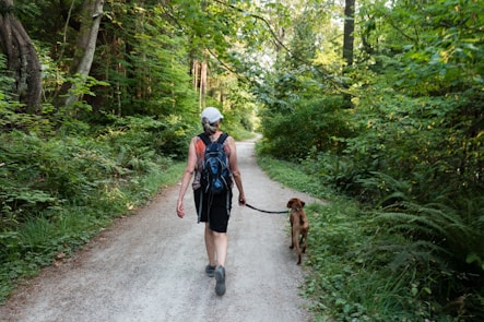2 women walking on road with brown dog during daytime
