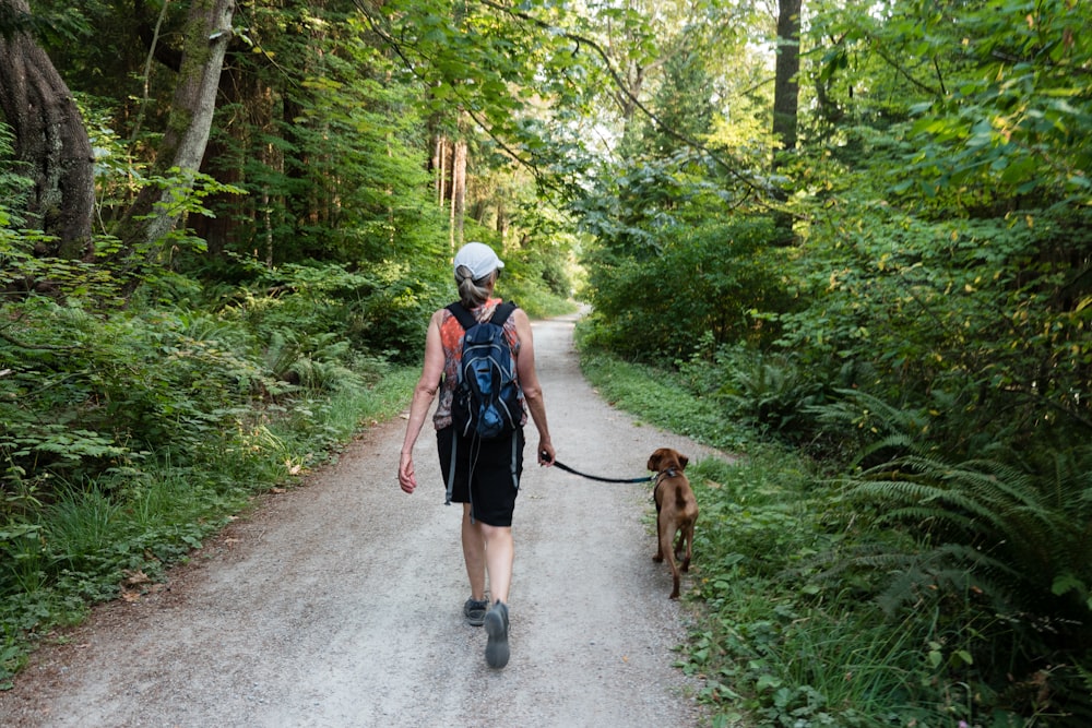 2 donne che camminano sulla strada con il cane marrone durante il giorno