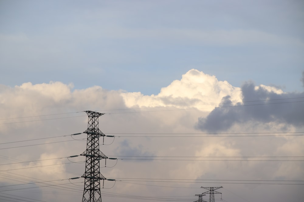 poteau électrique noir sous des nuages blancs pendant la journée