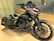 A custom motorcycle with a dark, metallic design featuring shark teeth artwork on the fairing. The bike has a military theme with star insignias and yellow stripes on the side bags. It also boasts large black wheels and a sleek black exhaust system.