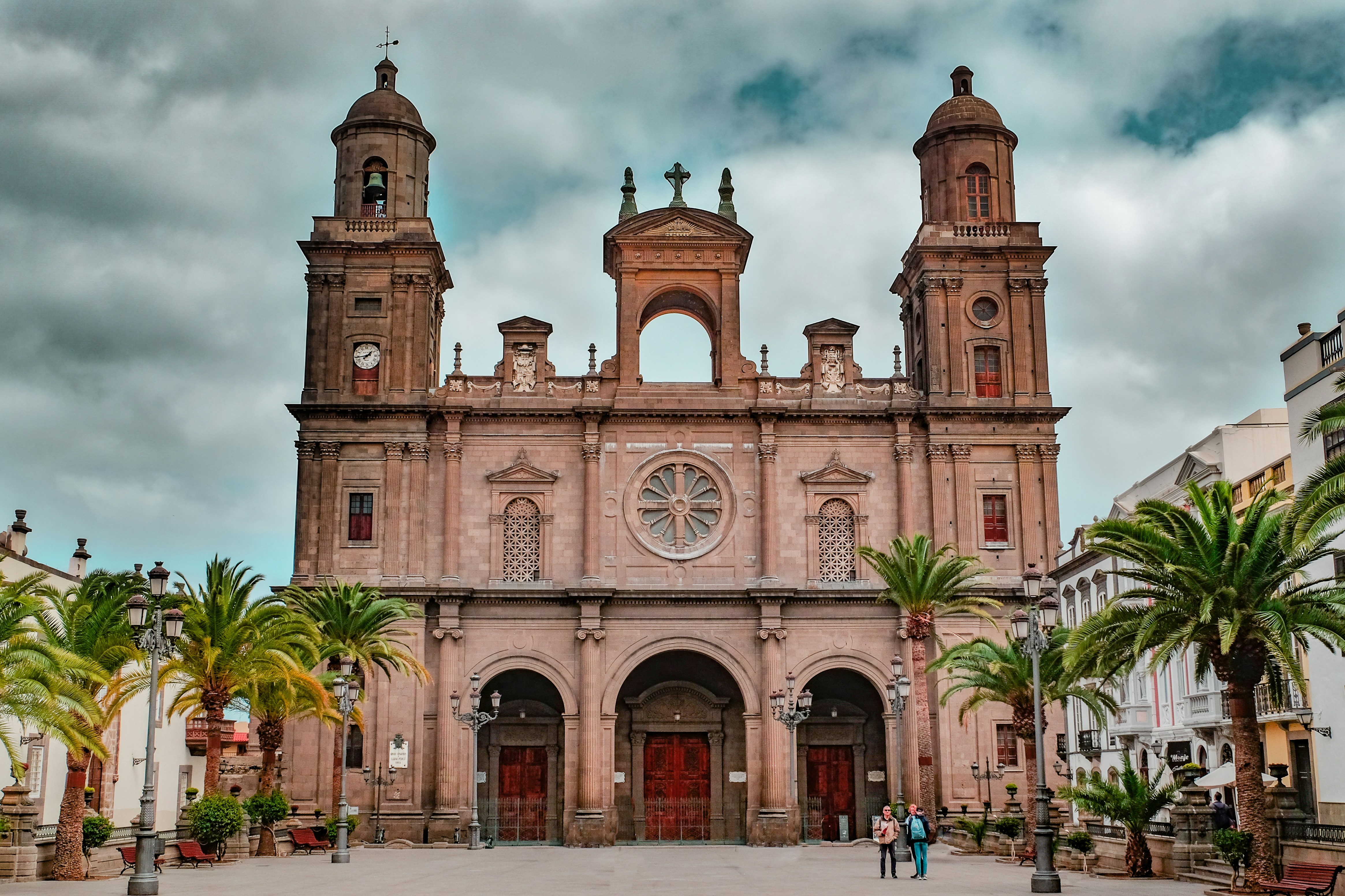 personnes marchant près d’un bâtiment en béton brun pendant la journée
