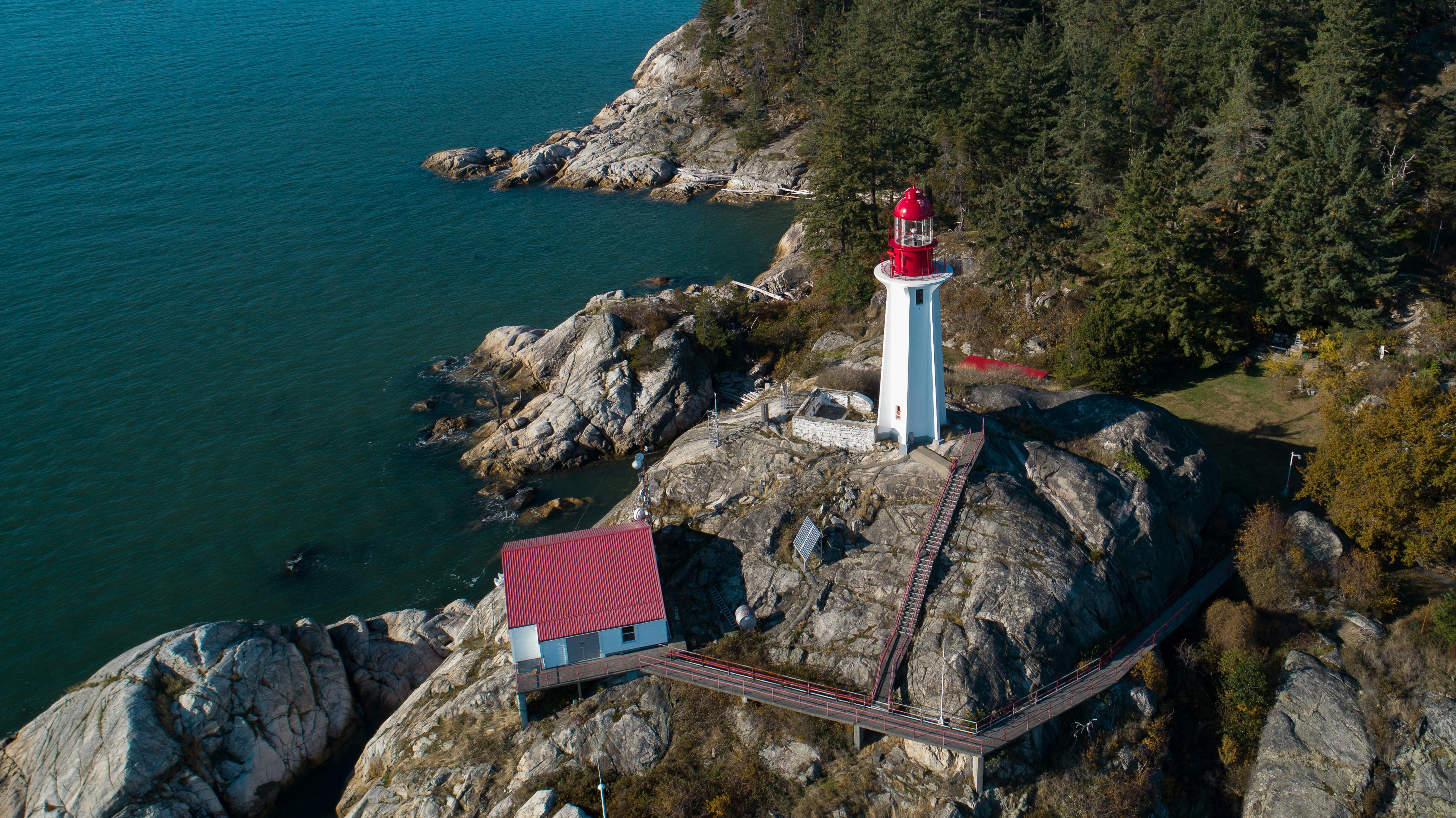 white and red lighthouse on brown rock formation near body of water during daytime