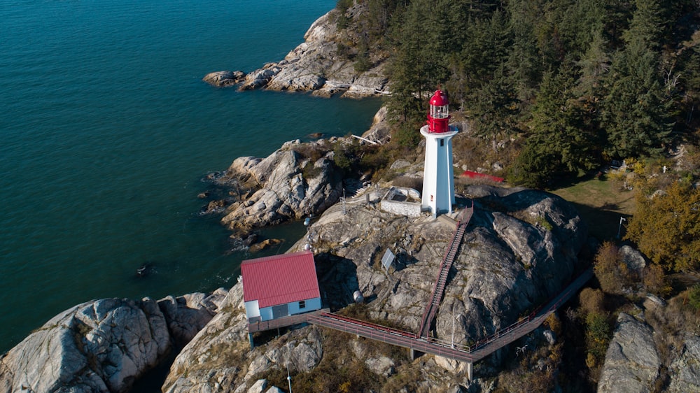 white and red lighthouse on brown rock formation near body of water during daytime