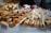 An assortment of pastries and cakes is displayed on platters, featuring a variety of treats topped with fresh berries, icing, and cream. The arrangement includes cupcakes, loaf cakes, and tarts, with labels indicating different flavors.