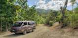 Mobile medical unit parked in a remote village surrounded by lush greenery.