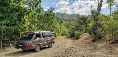 Mobile medical unit parked in a remote village surrounded by lush greenery.