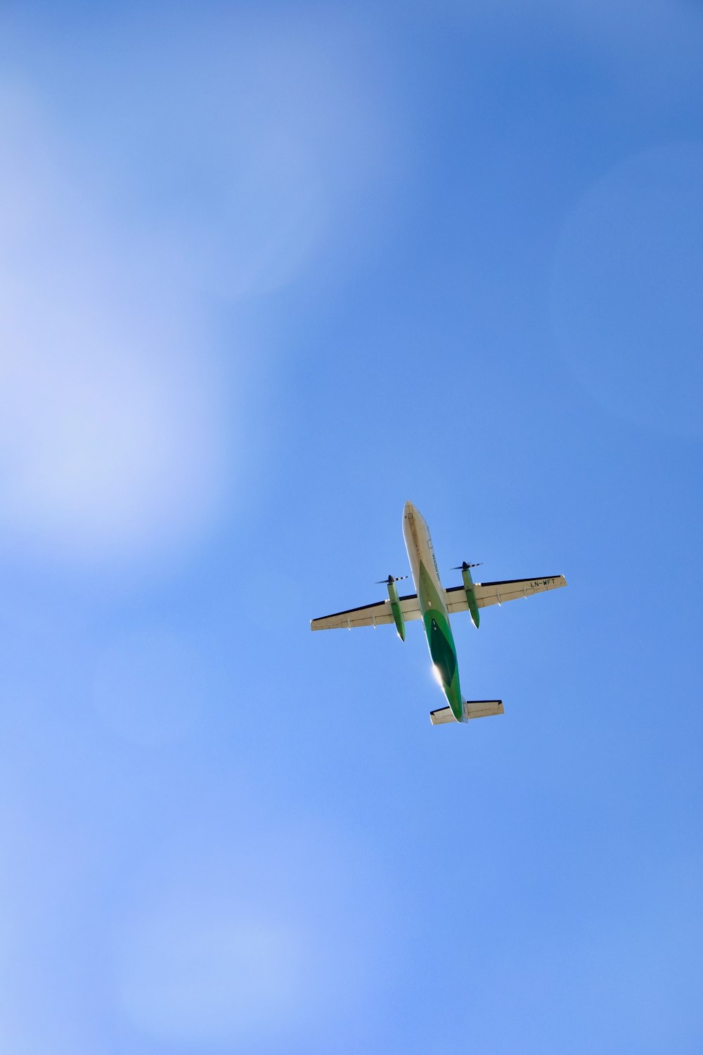 white and green plane in mid air during daytime