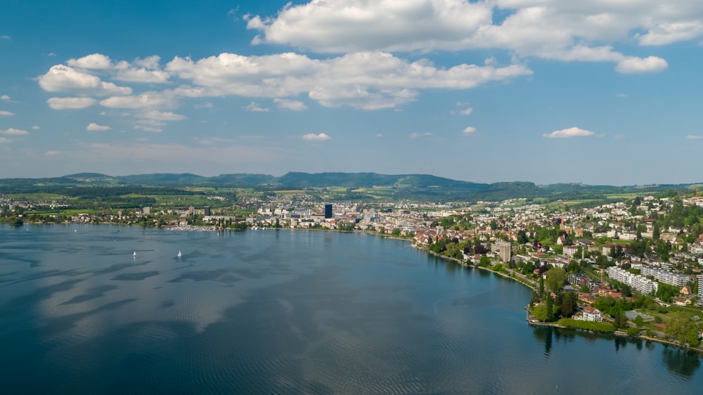 body of water near city buildings under blue and white sunny cloudy sky during daytime