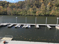 A peaceful river bend with a small boat tied to a rustic dock surrounded by autumn leaves.