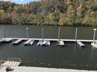 A peaceful river bend with a small boat tied to a rustic dock surrounded by autumn leaves.