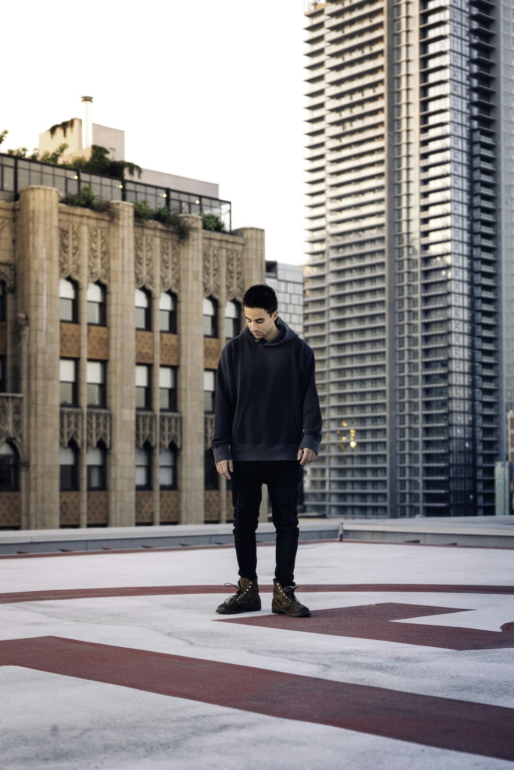 man in black jacket standing on red and white basketball court during daytime