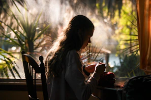 A serene lifestyle scene with a person journaling by a sunlit window surrounded by plants